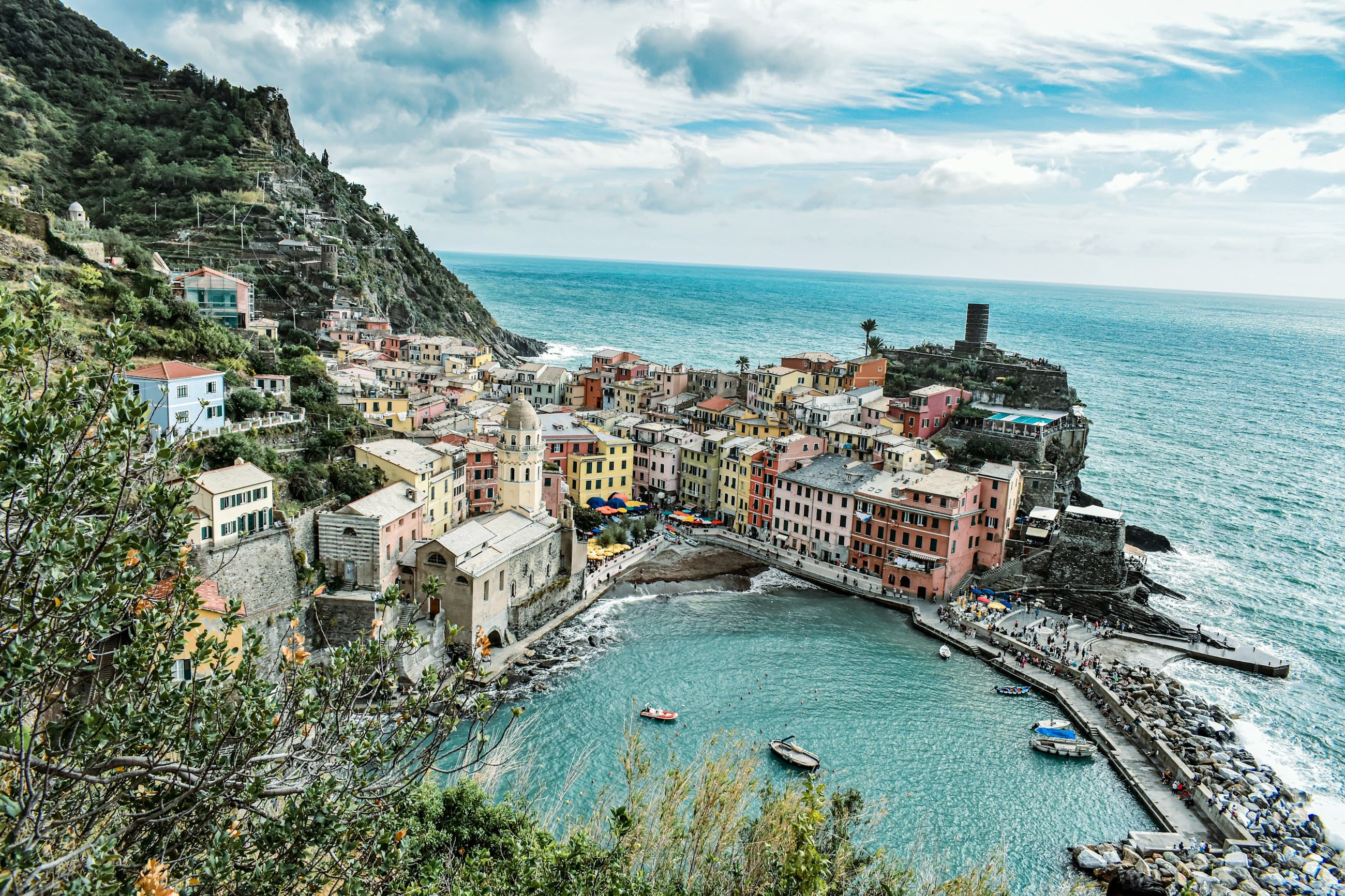 The harbour at Vernazza seen from above, coloured houses packed around a small bay with boats drawn up on the slip.